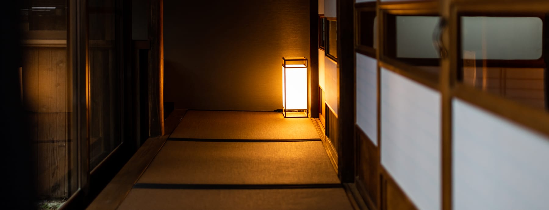 A dim wooden corridor lit by a single lantern