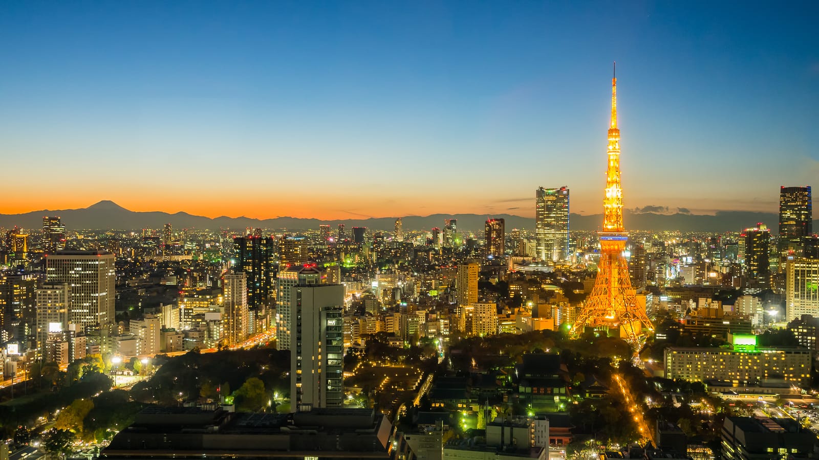 Tokyo's skyline at dusk, Tokyo Tower glowing gold above the city with Mount Fuji's silhouette on the horizon