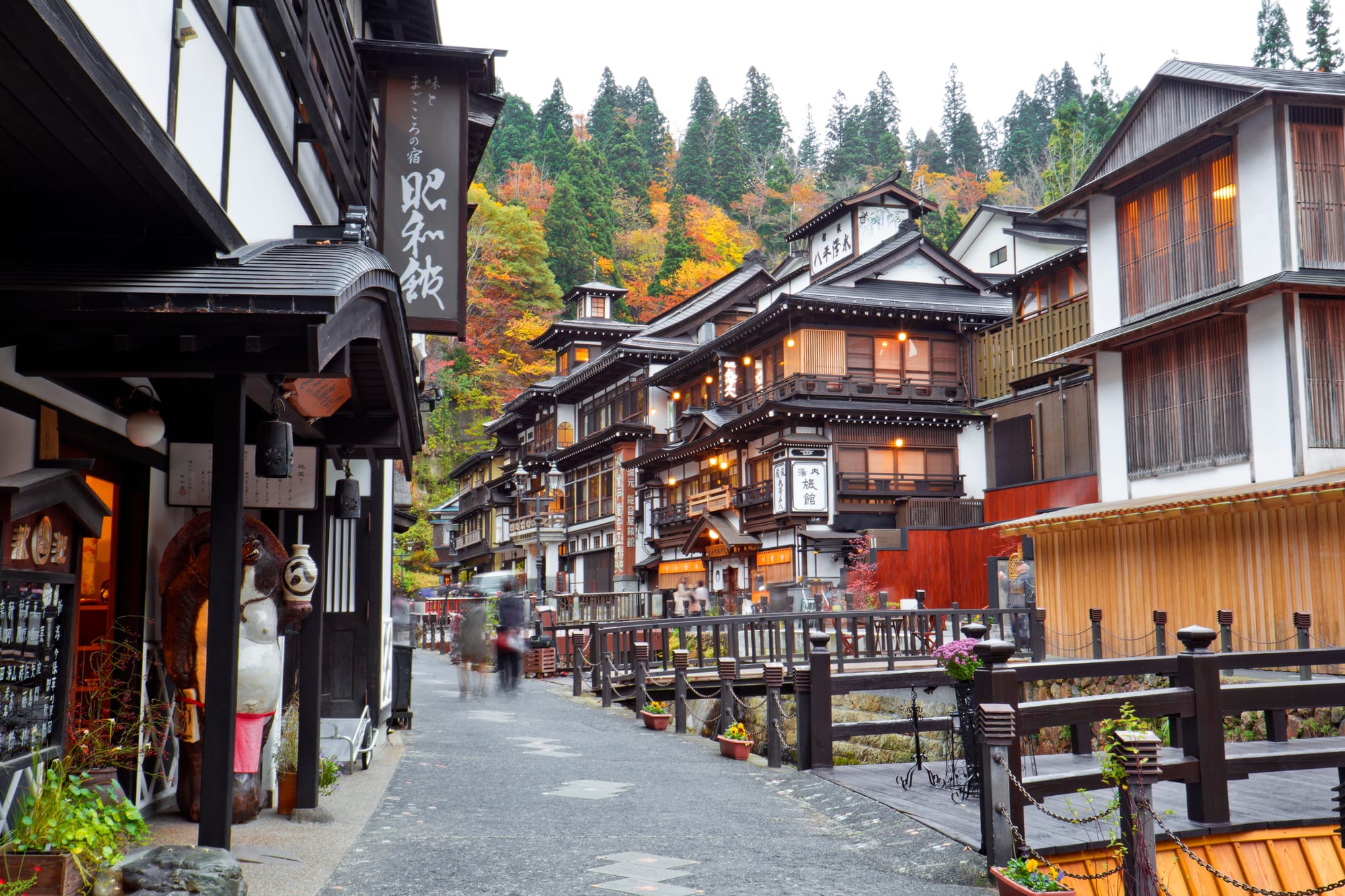 A historic hot-spring town at dusk, wooden inns lit against a hillside of autumn colour