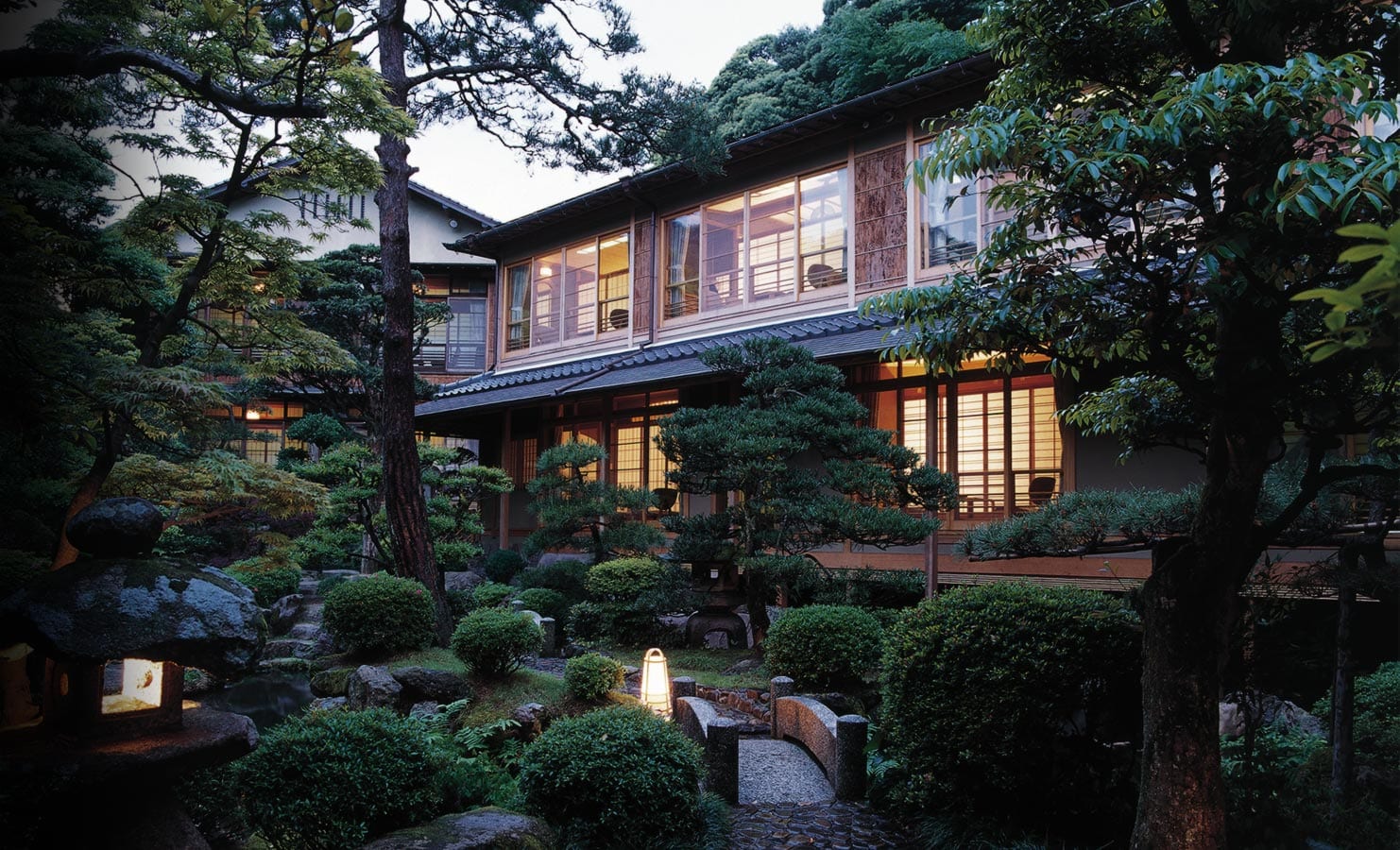 Kinosaki Onsen's willow canal lined with wooden ryokan at dusk