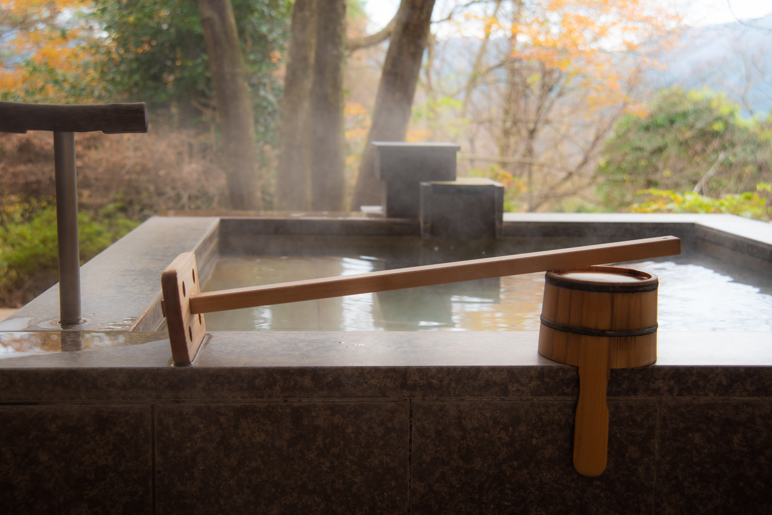 A stone-lined onsen bath with steam rising, northern Japan