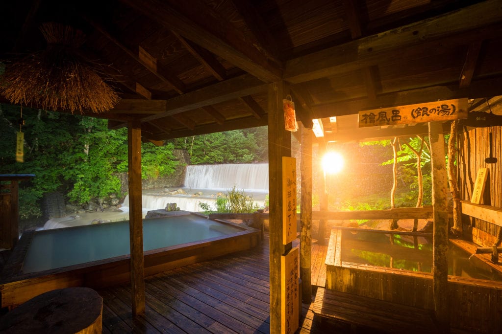 An open-air bath at Nyuto Onsen surrounded by autumn beech forest