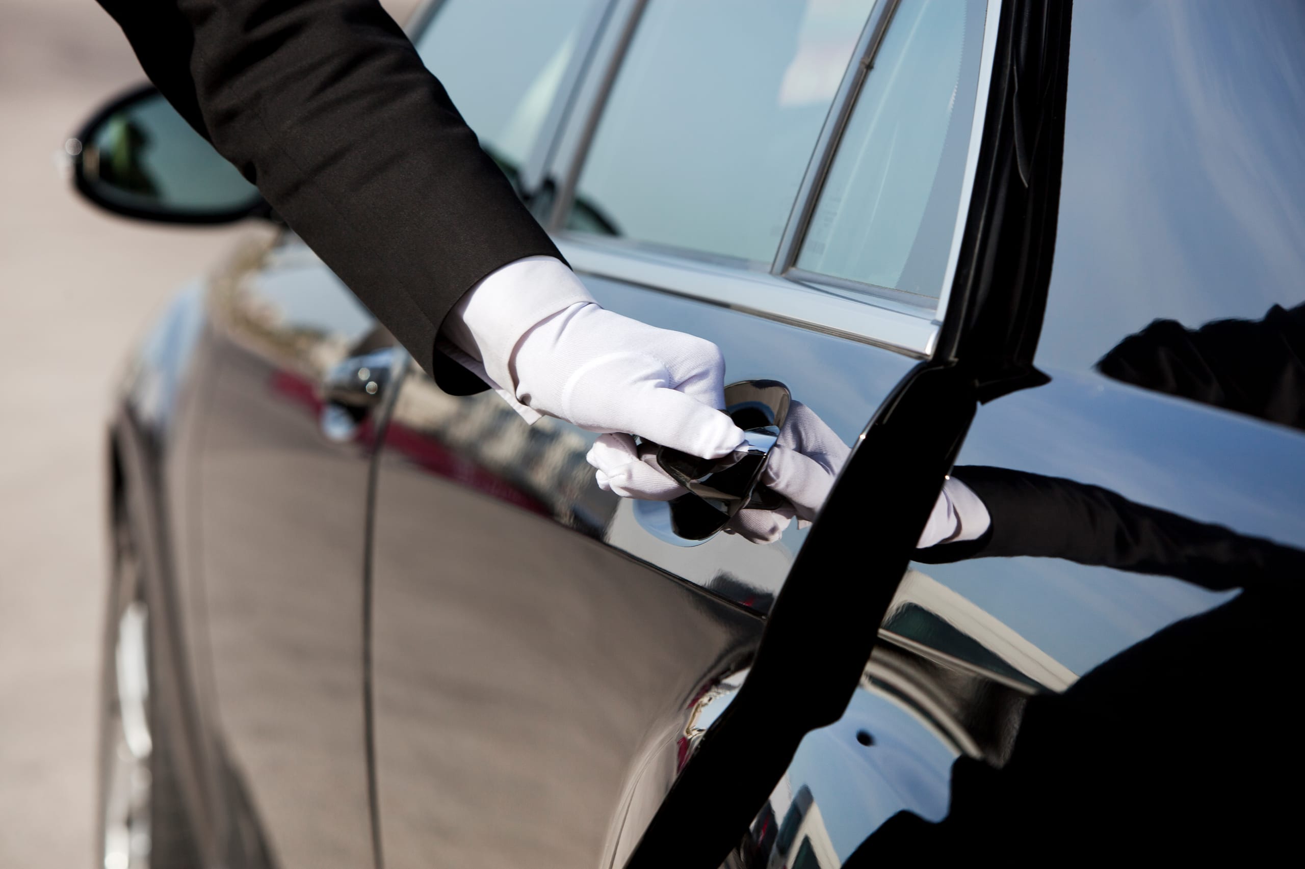 A chauffeur opening the door of a private car
