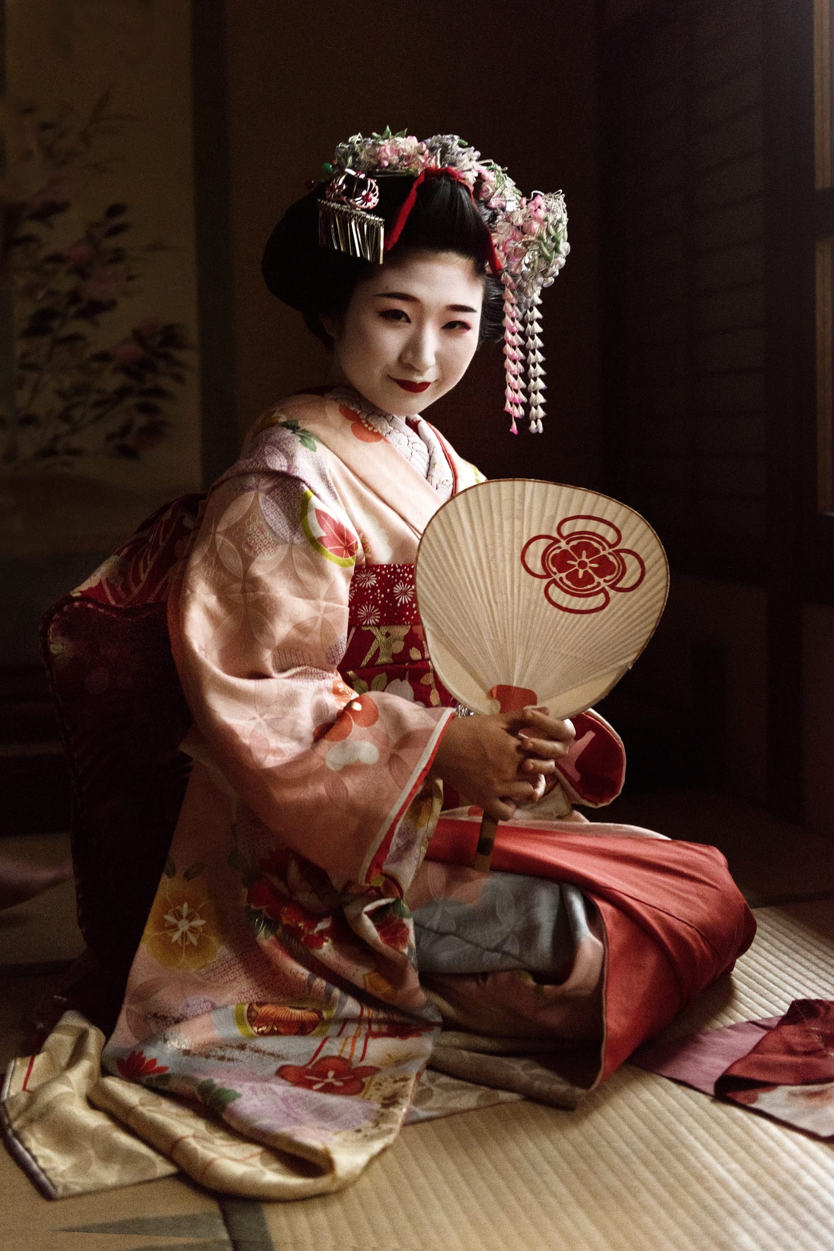 A maiko seated on tatami during an ozashiki gathering