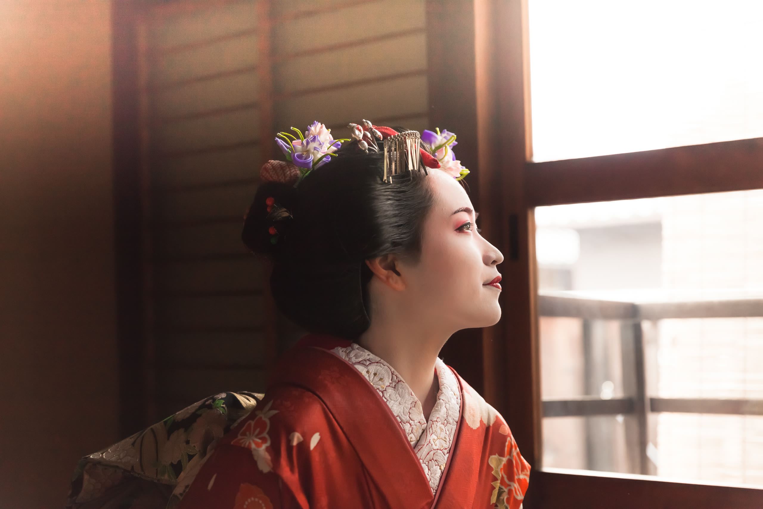 A maiko seen through a Gion teahouse window