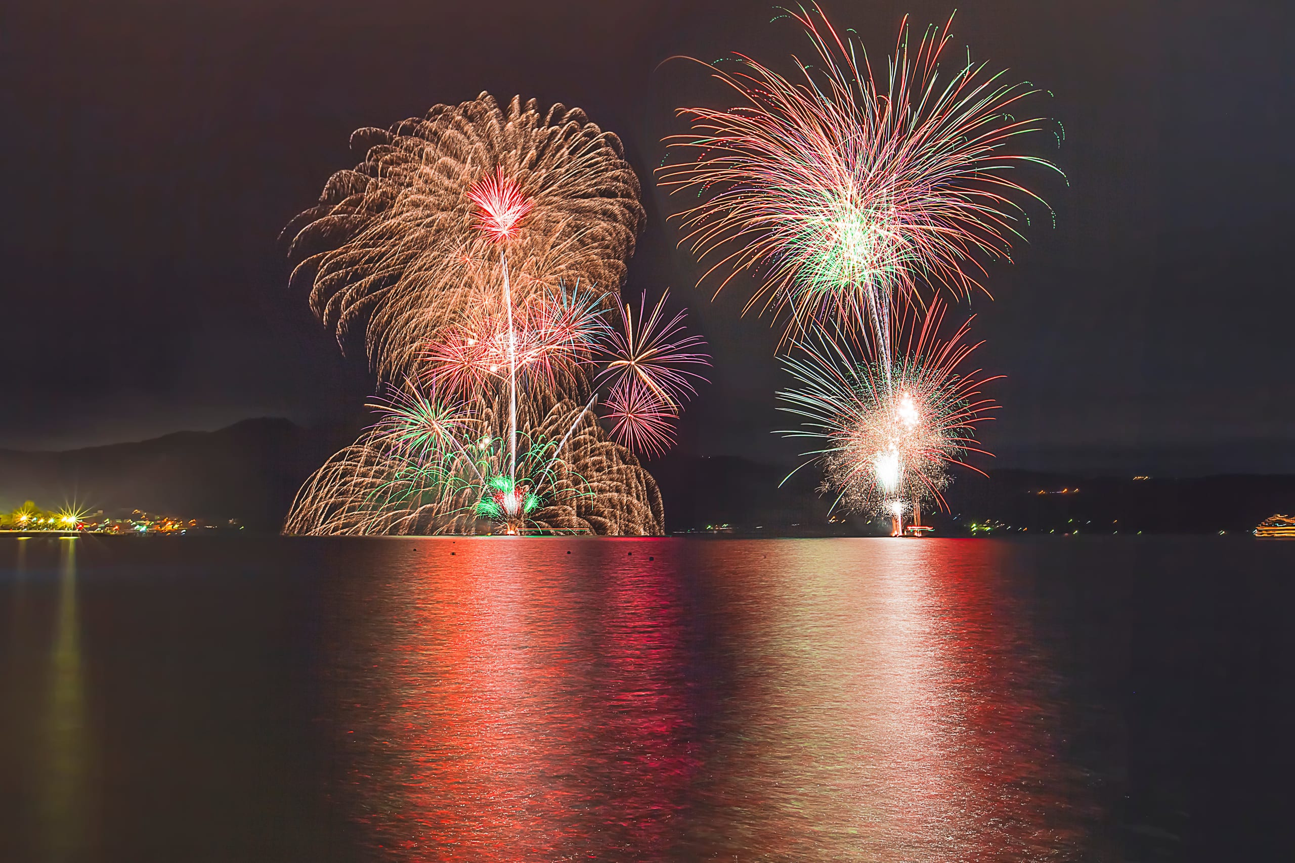 Fireworks opening over Lake Toya at night, seen from the shore